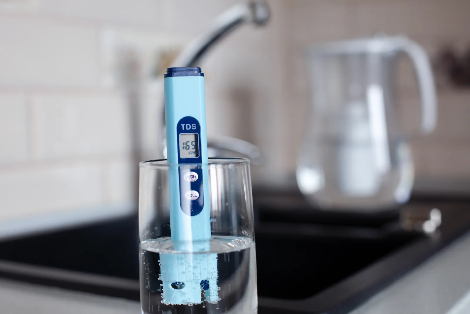 TDS meter reading in a glass of water at the kitchen sink